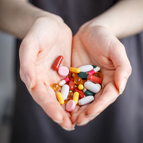 The two hands of a woman with a lot of colorful pills